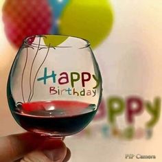 a hand holding a wine glass with the words happy birthday written on it