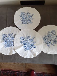 four blue and white plates sitting on top of a table next to a red rug