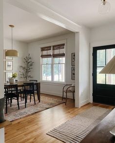 a living room filled with furniture and a dining table in front of a window on top of a hard wood floor