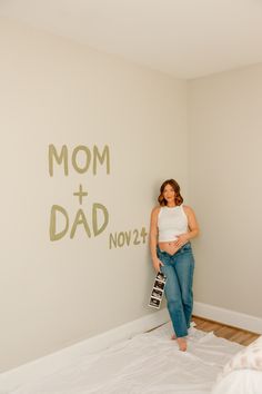 a woman standing next to a wall with the words mom and dad painted on it