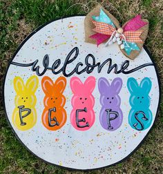 a welcome sign with painted bunnies and the words peeps on it in front of grass