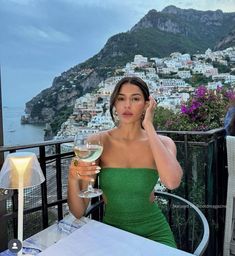 a woman in a green dress holding a glass of wine