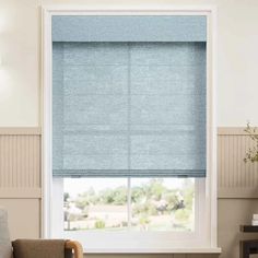 a living room with a couch, chair and window covered in blue roman blind blinds