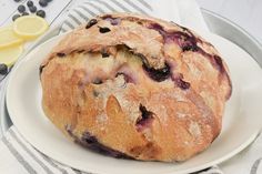 a loaf of blueberry bread sitting on top of a white plate next to lemons