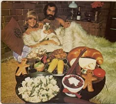 a man and woman sitting on the floor with food