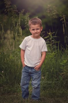 a young boy is standing in the grass