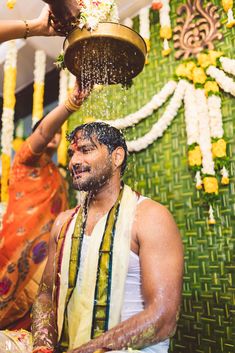 a man is being sprayed with water on his face by another man in the background