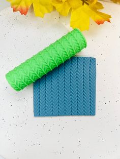 a blue and green object sitting on top of a white table next to yellow flowers