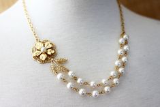 A beautiful gold plated  flower  is set with a pearl , set on a filagree and attached to a gold plated leaf trailed by a two strands of hand wired linked off white Swarovski glass pearls of 8 mm. The necklace is finished with gold plated cable chain, necklace measures 16 .5" long. Lobster clasp. H A N D M A D E  * We hand make all pieces in our Water Mill New York studio * We source eco friendly packaging and materials, including recyclable mailers! FREE BOX AND WRAP ON EVERY ORDER P R O D U C T I O N ∙ T I M E S All items are made to order, our average production time is 1-3 business days but can take up to 5 sometimes. If you need it sooner, please leave a message in the "note to seller" so we can try to speed things up for you! E X P E D I T E D ∙ O P T I O N S Each drop down menu has e Gold Flower-shaped Jewelry For Wedding, Gold Flower Shaped Jewelry For Wedding, Elegant Flower Shaped Pearl Chain Jewelry, Delicate Gold Pearl Bridal Necklace, Delicate Gold Bridal Necklace With Pearls, Gold Pearl Flower Jewelry, Gold Pearl Bridal Necklace For Mother Of The Bride, Mother Of The Bride Gold Pearl Bridal Necklace, Classic Gold Bridal Necklace For Wedding