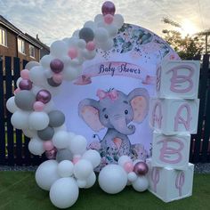 an elephant themed baby shower is displayed in front of a gate with blocks and balloons