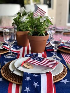 an american flag table cloth with place settings and utensils on it, along with potted plants