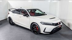 a white car parked in a garage with black rims and red brake pads on it