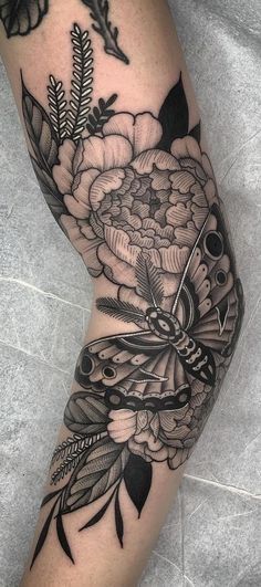 a woman's leg with black and white tattoos on it, including an image of flowers