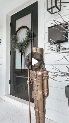 a statue of a man holding a cane stands in front of a door with wreaths on it