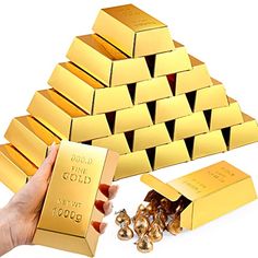 a hand holding a gold bar next to several pieces of gold in the shape of a pyramid