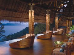 the inside of a restaurant with wooden tables and chairs, overlooking an ocean at night