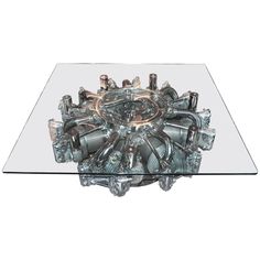 a glass table with an engine design on it's center piece and metal fittings