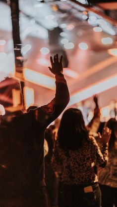 a group of people standing next to each other in front of a stage with their hands up