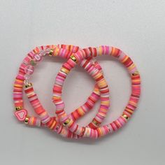 three bracelets with pink, orange and yellow beads on white table top next to each other