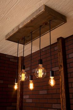 three light bulbs hanging from the ceiling in a room with brick walls and wood beams