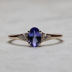 a tan gold ring with an oval blue sapphire and three diamonds