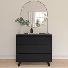 a black dresser with a round mirror on top and plants in vases next to it