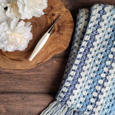 a blue and white crocheted blanket sitting on top of a wooden cutting board