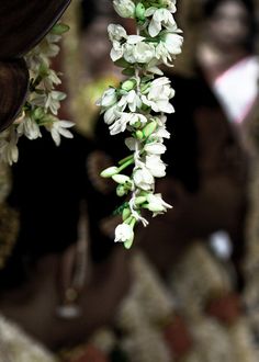 white flowers are hanging from the ceiling in front of two women with dark hair and black clothing