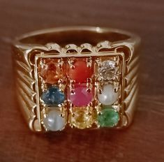 Handmade Solid 14k Gold Navratna Ring, 9 Precious Natural Gemstones Ring, Square Shape Ring, Solid 14k gold Rings, Navratna Rings, Rings Gift For her. Metal Used - 14K Gold All Natural Real Gemstone -  (Starting clockwise with Blue Sapphire, Cat's eye, Yellow sapphire, Emerald, Diamond, Pearl, Coral, Hessonite and Ruby in the centre) No. of Real Natural Gemstones :- Used - 9 pcs.  Size of 9 Gemstone - 3.50 mm. Round Weight of Nine Navratna Gemstone Used - 2 CTS Ring Weight - 11 gm Ring Size - Av Navaratna Ring, Navratna Ring, Ring Square, International Jewelry, Natural Gemstone Ring, Rings Rings, 14k Gold Ring, Engagement Anniversary, Yellow Sapphire