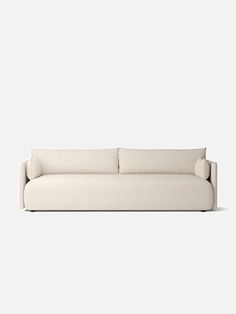 a white couch sitting on top of a white floor next to a wall mounted clock