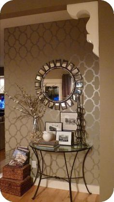 a living room with a mirror, table and pictures on the wall next to it