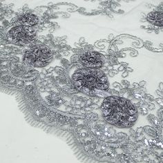 silver sequins and beads on white fabric with intricate lacework, closeup