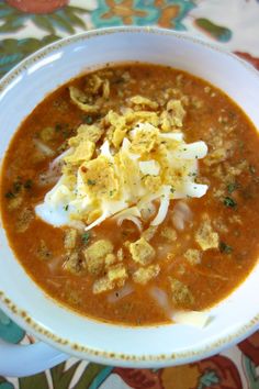 a white bowl filled with soup on top of a floral table cloth and topped with sour cream