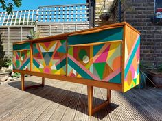 a colorful painted cabinet sitting on top of a wooden deck