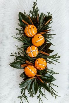 an arrangement of oranges and greenery on a white furnishing