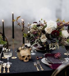 the table is set with candles, flowers and skull head decorations for an elegant halloween party