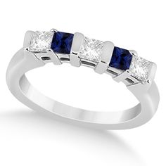 a white gold ring with three princess cut diamonds and blue sapphires on the sides