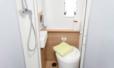 a small bathroom with a toilet, sink and shower head mounted on the wall next to it