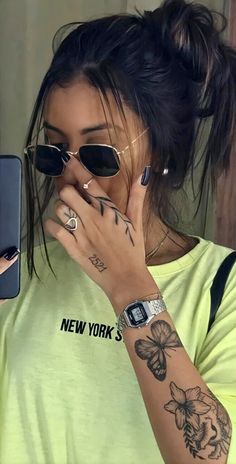 a woman with tattoos on her arm holding a cell phone