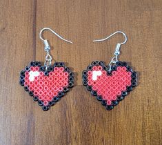 a pair of red and black heart shaped beaded earrings on top of a wooden table