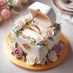 there is a wedding cake with flowers on the top and an open ring box in the middle