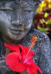 a statue with a red flower in its hand