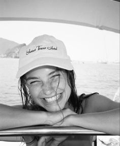 black and white photo of smiling woman in boat with hat on head looking out over the water