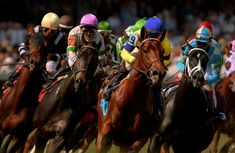 jockeys are riding their horses down the track at a horse race in front of an audience