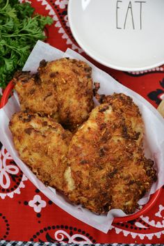 some fried food is sitting on a red and white table cloth next to a plate with parsley