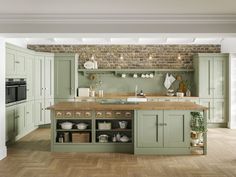 a large kitchen with green cabinets and wooden floors