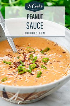 a white bowl filled with peanut sauce and topped with green onions