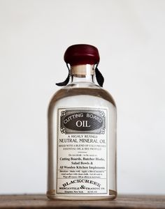 an old bottle of oil sitting on top of a wooden table