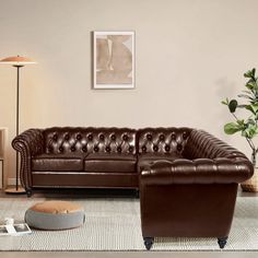 a brown leather couch sitting on top of a rug in a living room next to a lamp