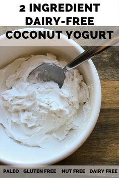 a white bowl filled with whipped cream on top of a wooden table next to a spoon